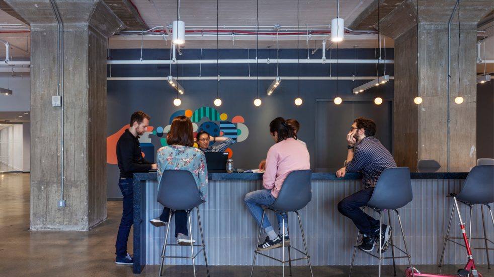 cowrokers meet at an island in the cafeteria, and a scooter is locked nearby