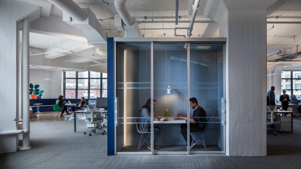 coworkers work together in small private meeting room that looks like a phone booth