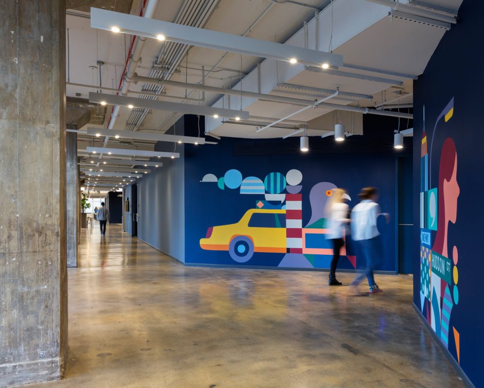 coworkers walk into a blue walled shortcut, lined with New York graphics by Adrian Johnson