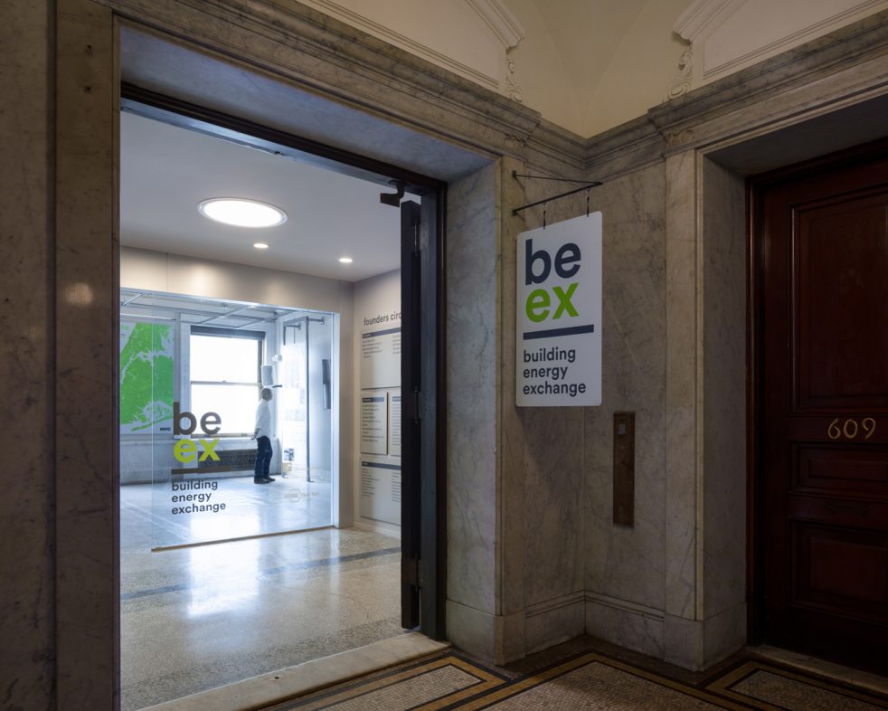 entrance to BE-Ex contrasts with the historic building hallway and a man reads an exhibition panel beyond