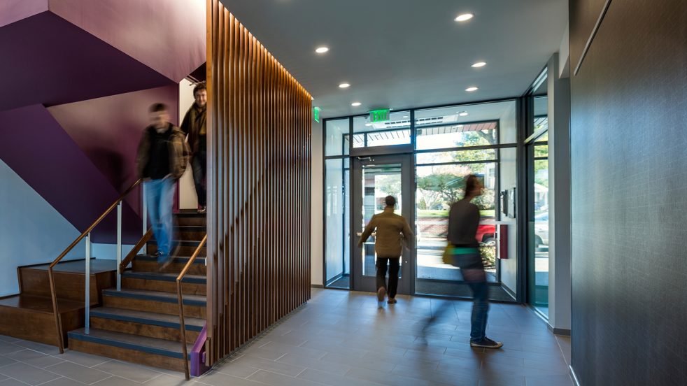 students descend decorative stair in the lobby and leave through the translucent residential-facing exit