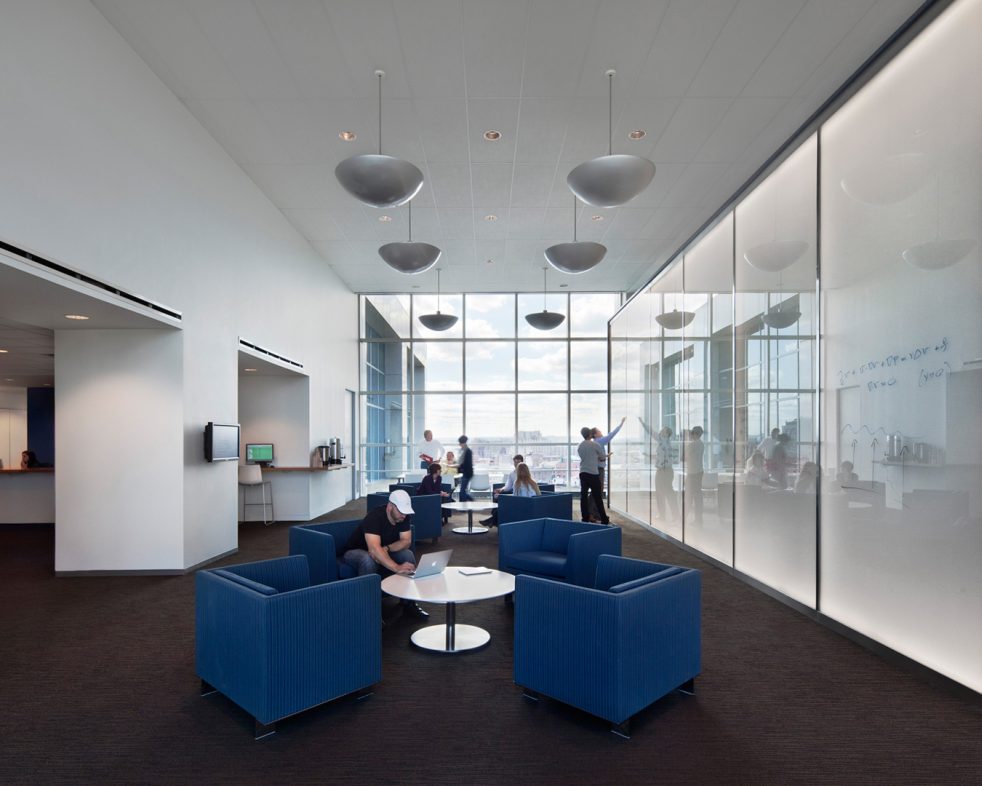 people work in open blue seating area while some work on writable glass panels