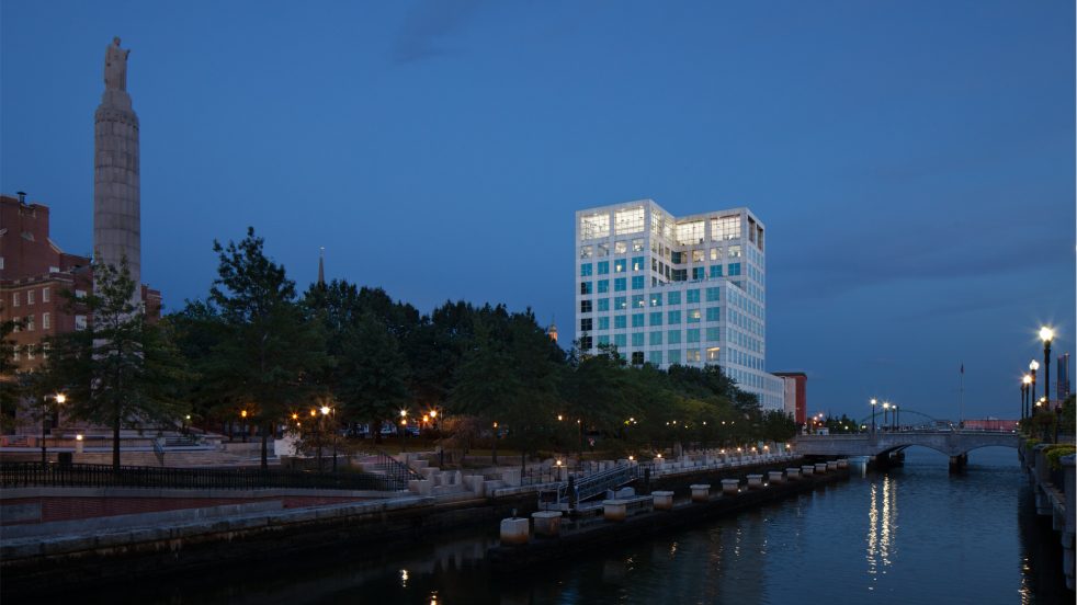 The two floors of ICERM illuminated at night at the top of an office building from the Providence River