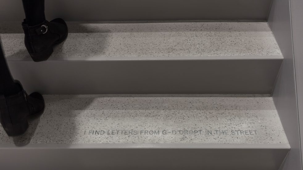 feet ascend terrazzo stairs inlaid with Walt Whitman quote that reads 