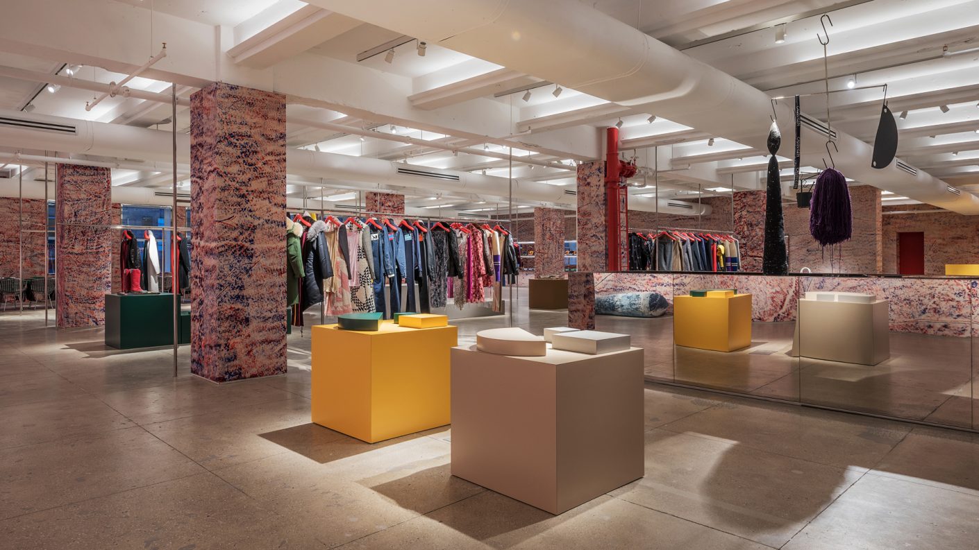 wide view of showroom with bright custom formica pedestals, Calvin Klein's collection, and Sterling Ruby's artwork