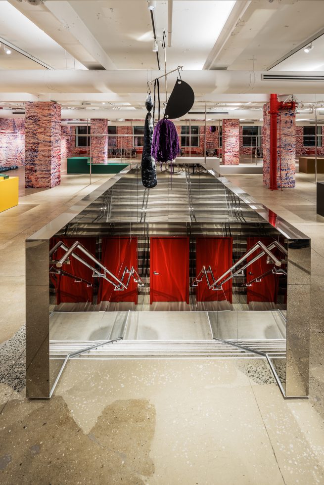 chrome lined staircase with Sterlin Ruby art suspended above and red door below