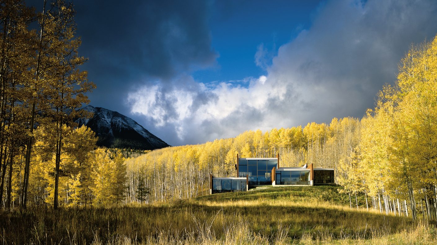 home in open field surrounded by yellow forest