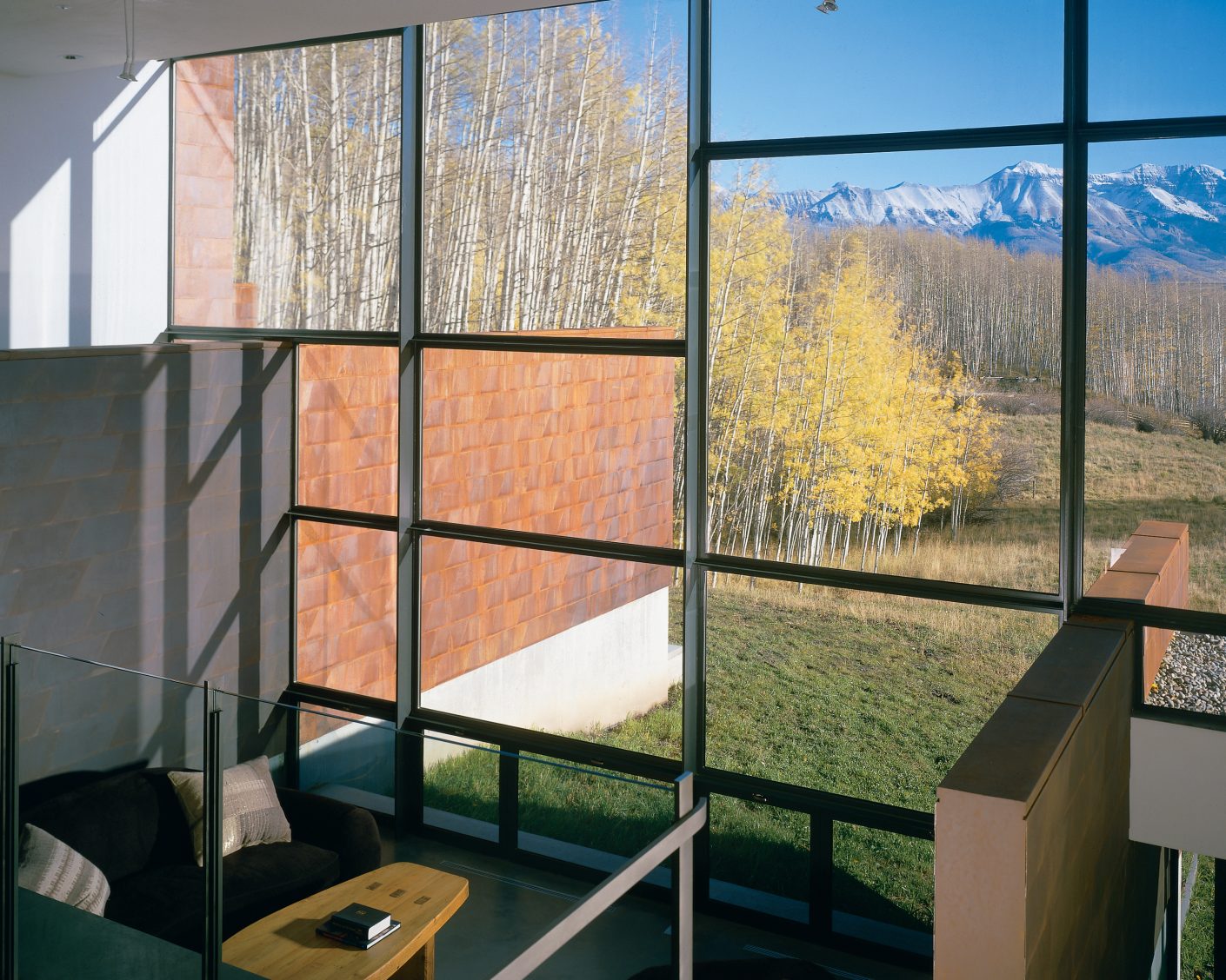 walls extend from a living area through a large window overlooking a valley and colorado mountains