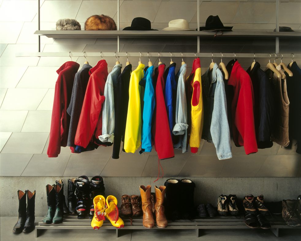 hats, jackets, and shoes in aligned before a patterned steel wall