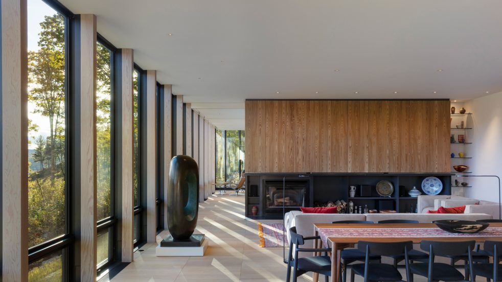 open dining and living area with floor-to-ceiling windows overlooking a valley