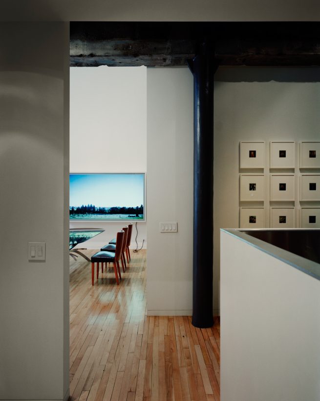 hallway towards dining area with illuminated work of art above