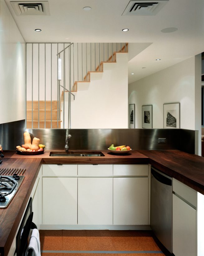 modern kitchen open to a staircase landing and gallery wall beyond