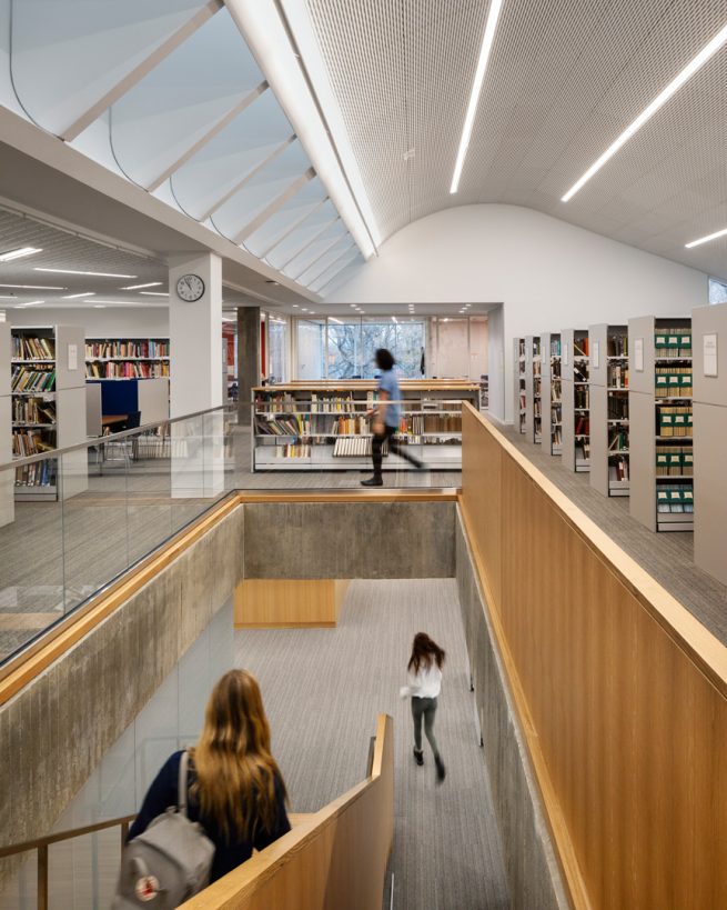 student descending staircase from second floor stacks