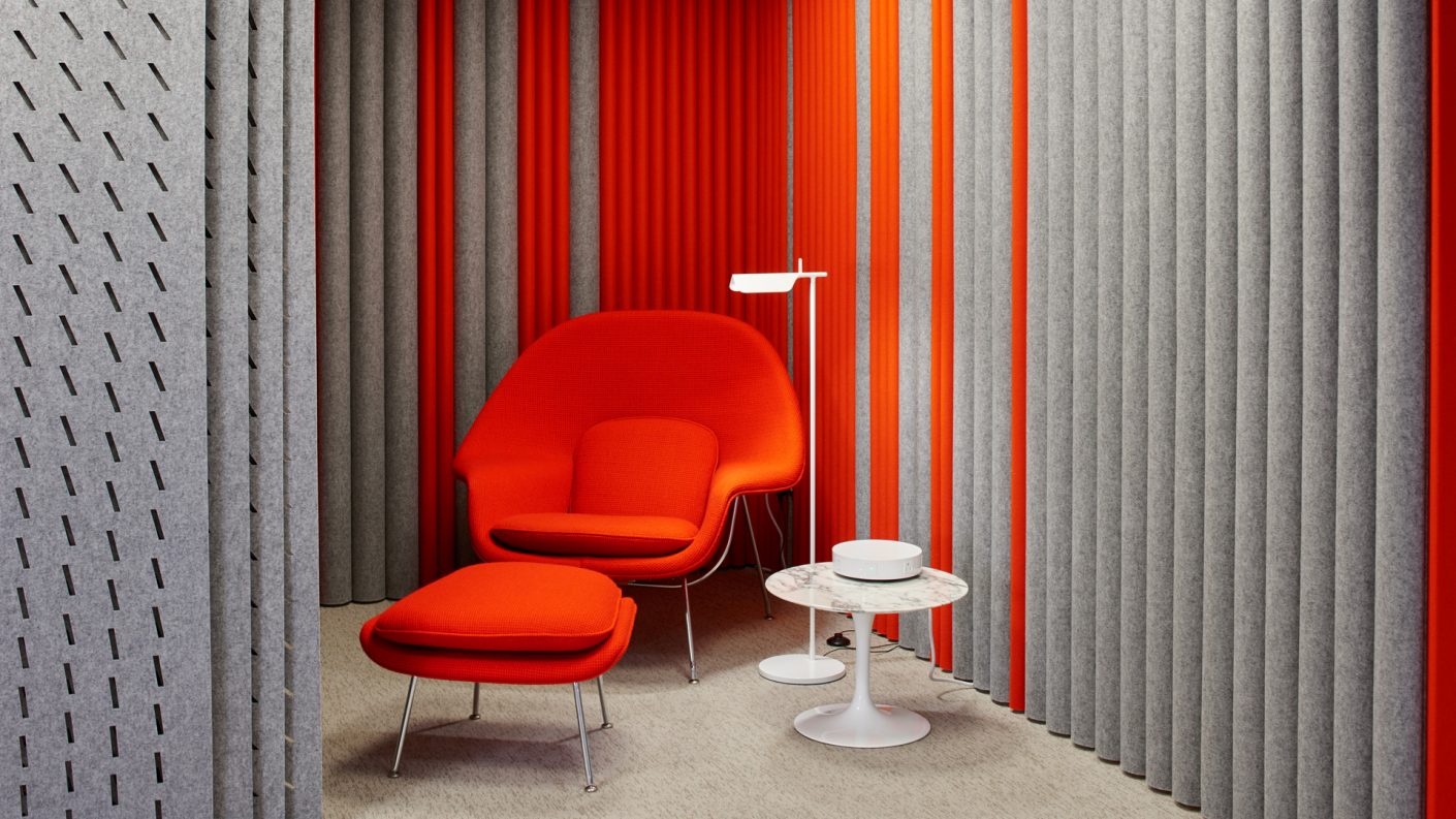red womb chair in a corner of a room lined with acoustic felt, ARO Plank, and ARO Array acting as screens