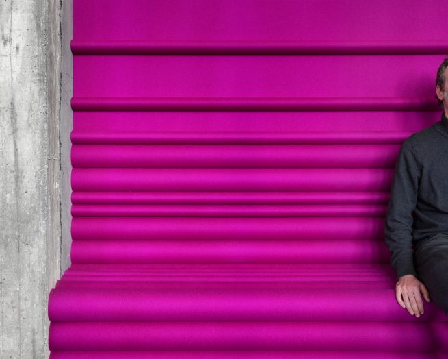 man sitting on custom pink ARO Planks assembled into a bench