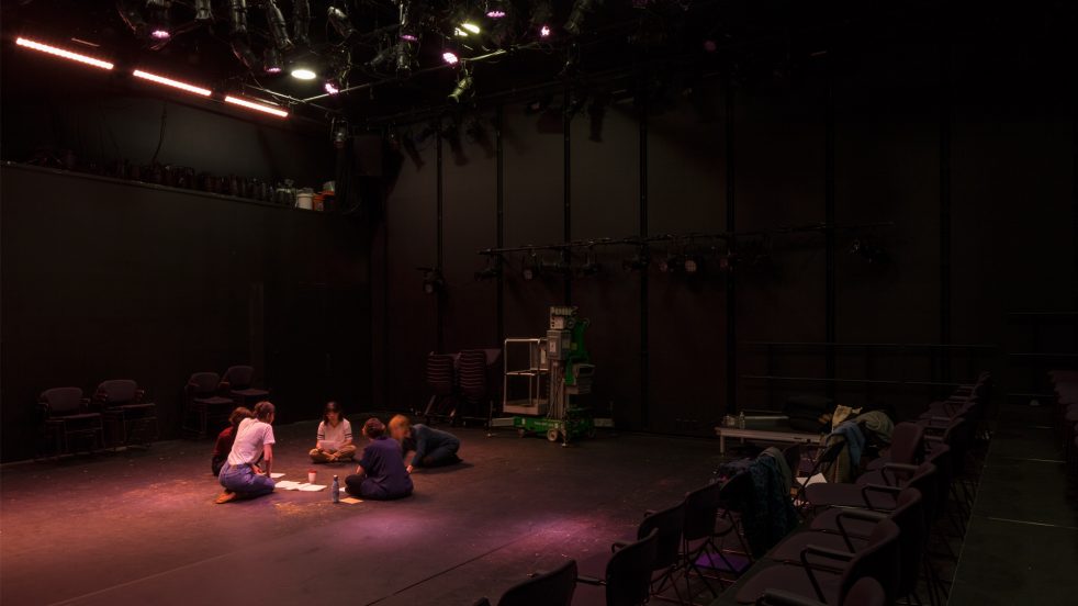 actors sit in circle reading through scripts in The Sam theater