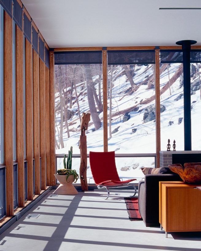 living space surrounded by floor-to-ceiling views of a snowy forest