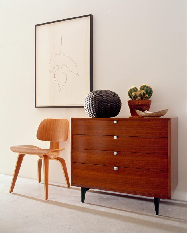 wooden dresser and chair below framed picture