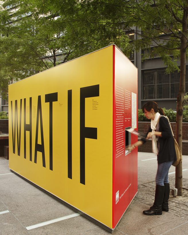 woman interacts with outdoor exhibition that reads What IF
