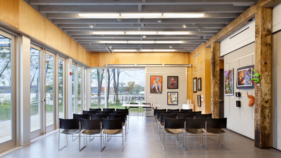 exhibition and lecture space with chairs and art overlooking river