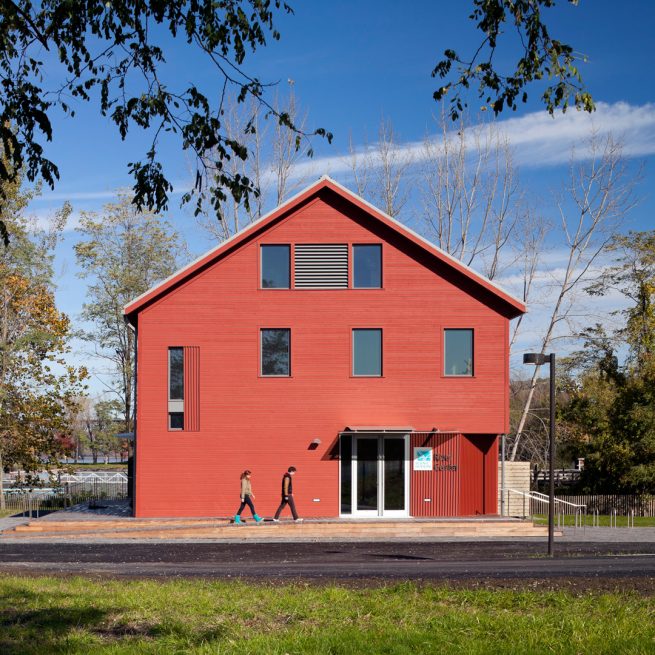 people ascend ramp in front of renovated red barn façade