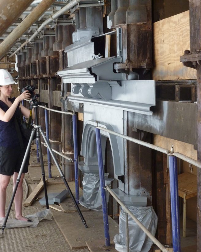 woman photographs new cast iron façade elements during construction