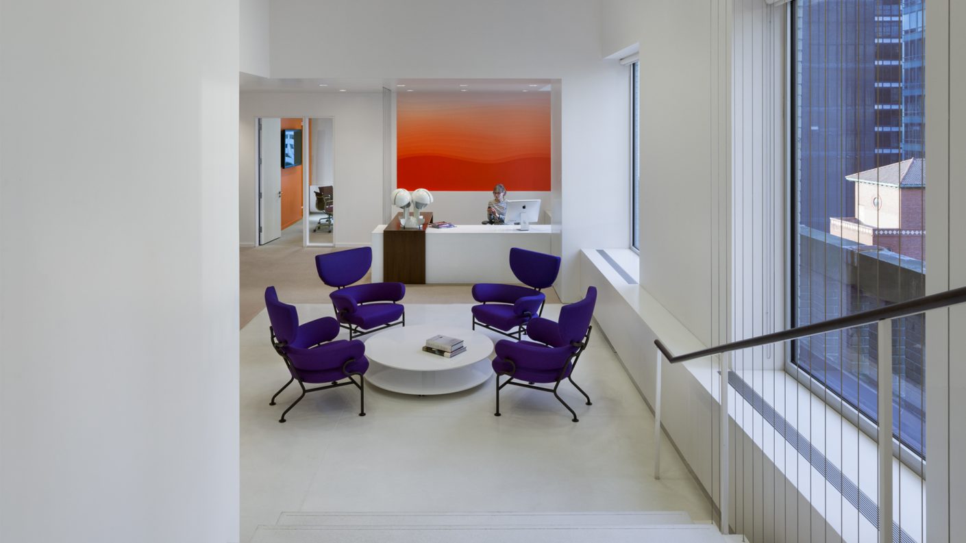 reception and waiting area of purple chairs at bottom of staircase