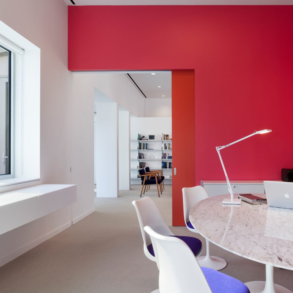 red wall with pocket door separating two work spaces