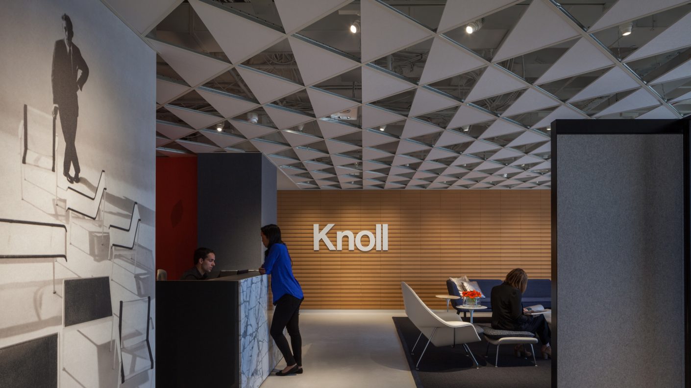 Woman speaks with male receptionist at Knoll Philadelphia under decorative ceiling installation