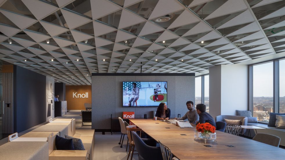 three people meet at large conference table in the center of the office