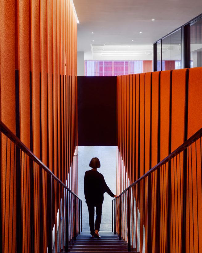 woman descends staircase wrapped in orange felt