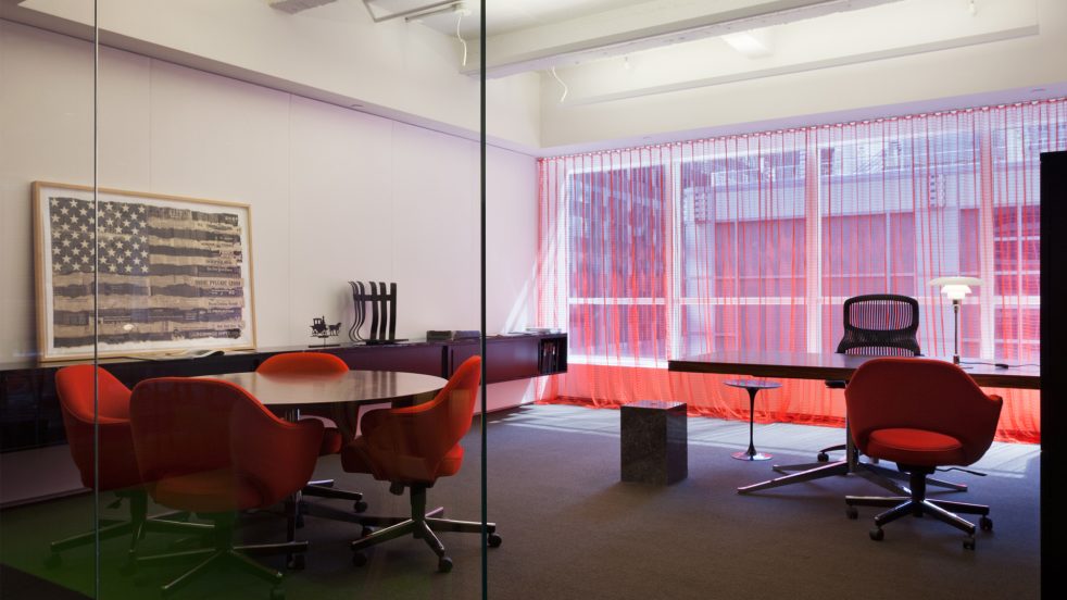 private office with transluscent red curtains drawn and a framed American flag