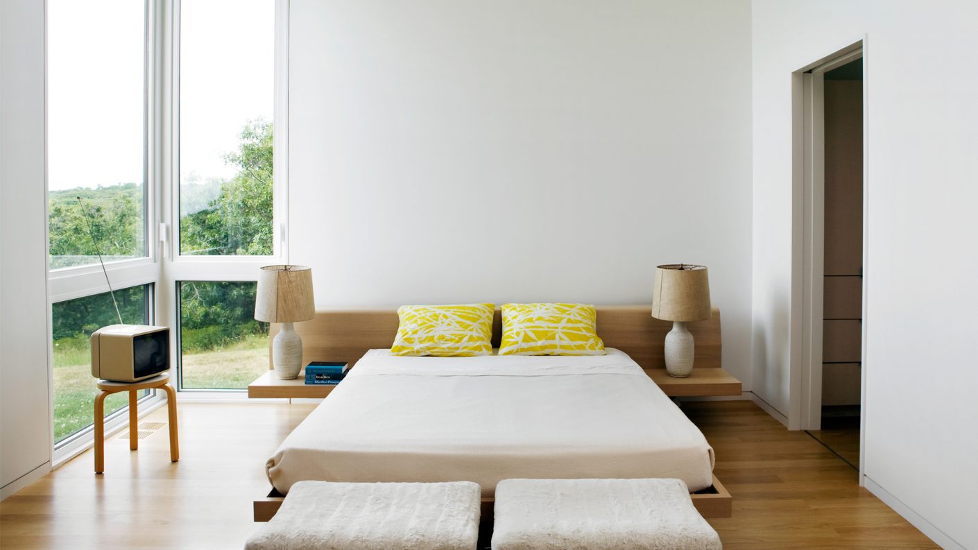 white bedroom with floor-to-ceiling windows in one corner