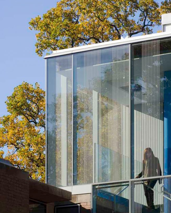 student descends stairs behind fritted glass façade