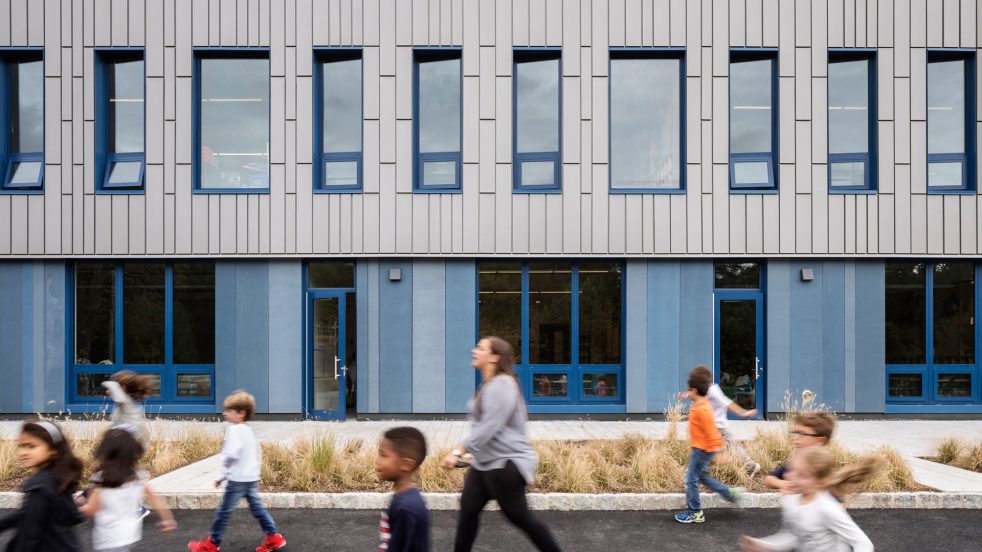 teacher and students walking past zinc and blue concrete façade