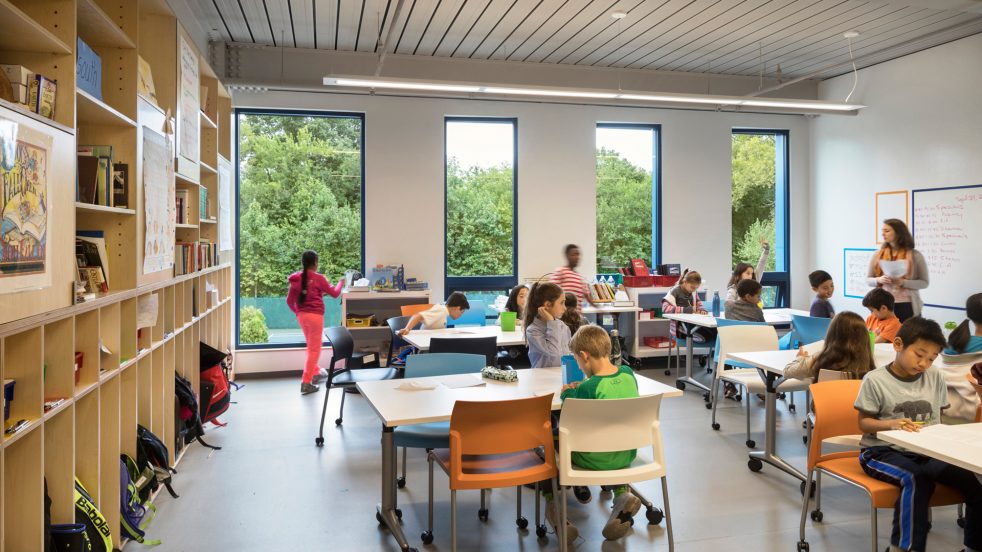 students in a bright classroom with large windows overlooking the natural landscape