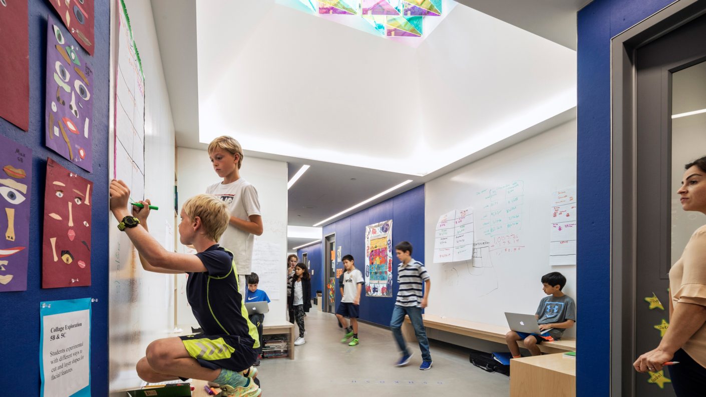 students work together in a breakout space under a hallway skylight