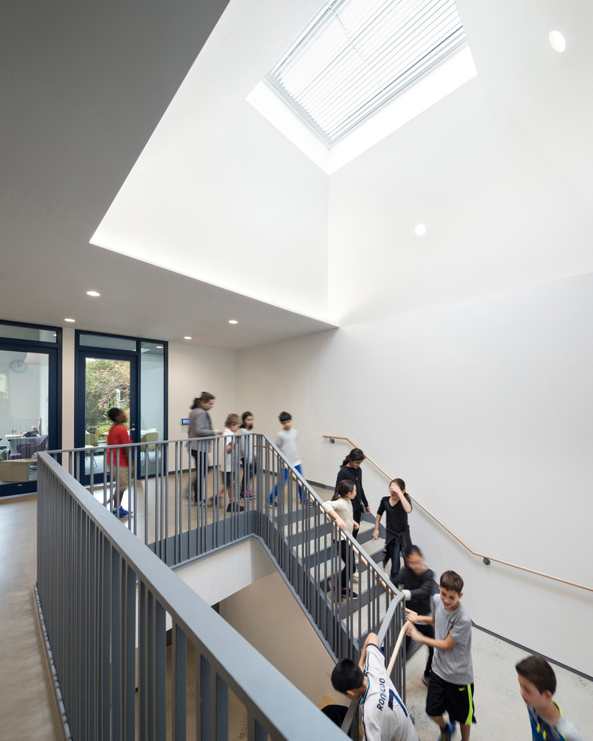 students descend wide staircase below prism skylight