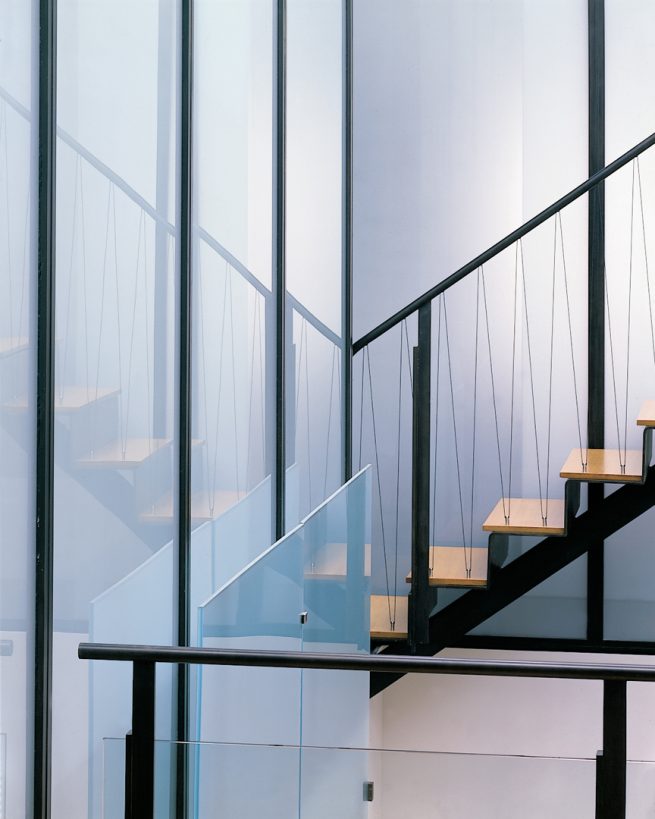 stair case runs along glass with cables connecting each stair to the rail