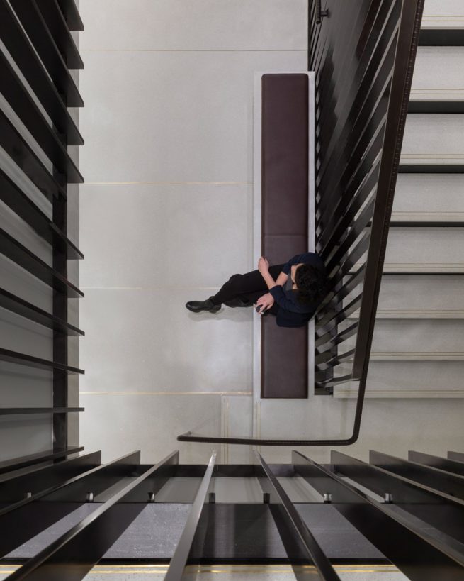 woman rests on bench next to staircase