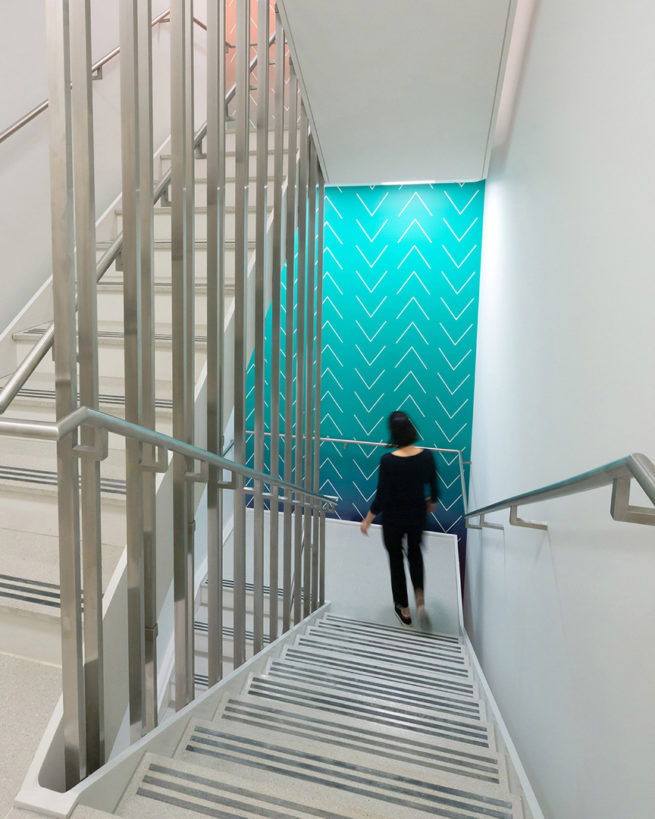 Woman descending fire stair with teal paint accent wall