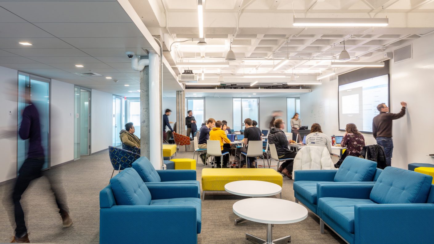 Large open workspace with couches, round tables, and writable wall