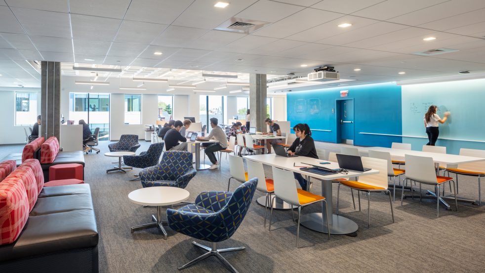 Large flexible workspace with people working on computers and working at blue writable walls