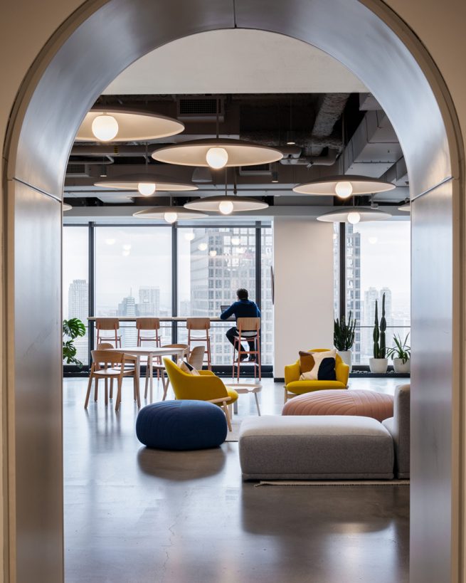 View from an archway of a person sitting at a bar working on a laptop overlooking a skyline