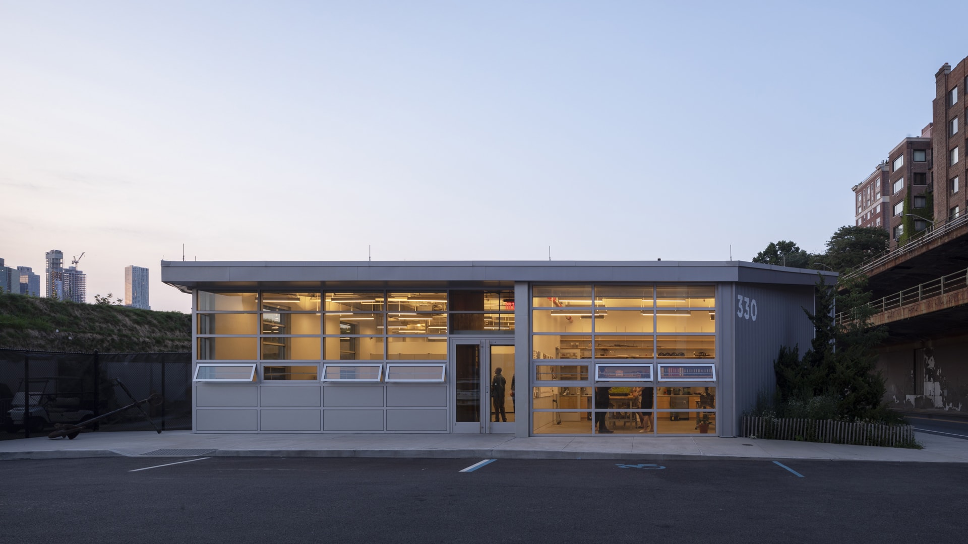 The Maintenance and Operations building at dusk with a view through glass windows of people working inside