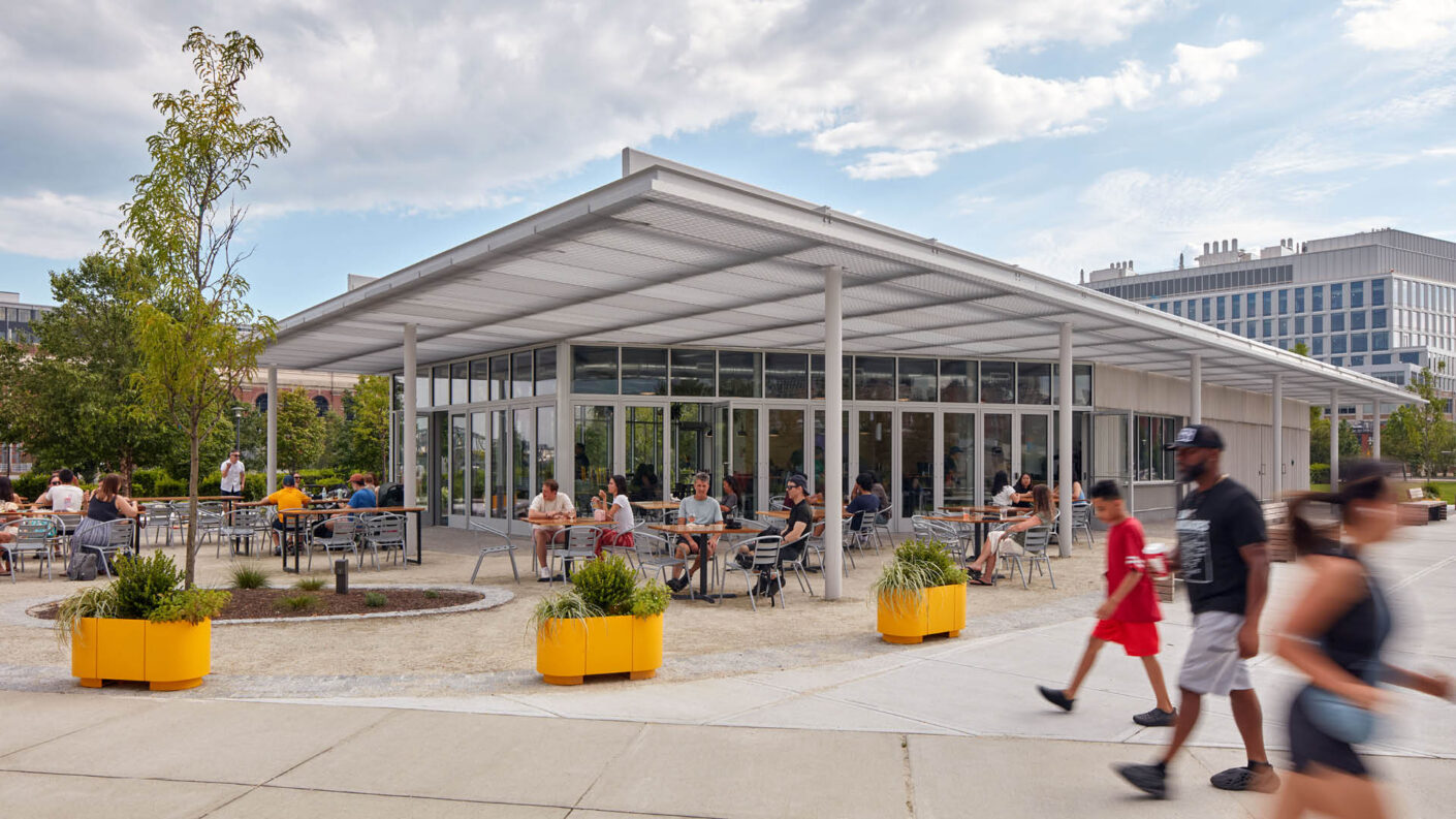 People gather under the canopy of a park pavilion