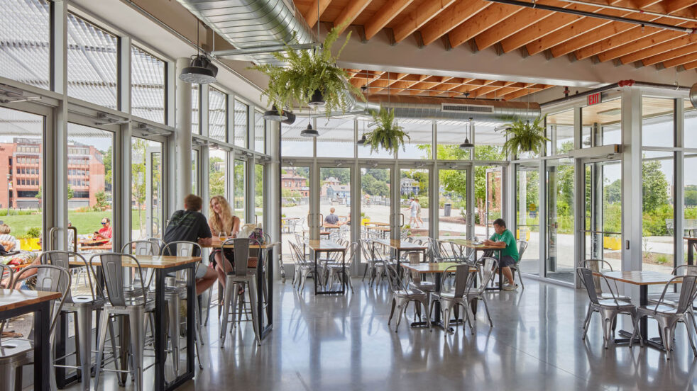 People enjoying beer indoors with views of a park beyond.