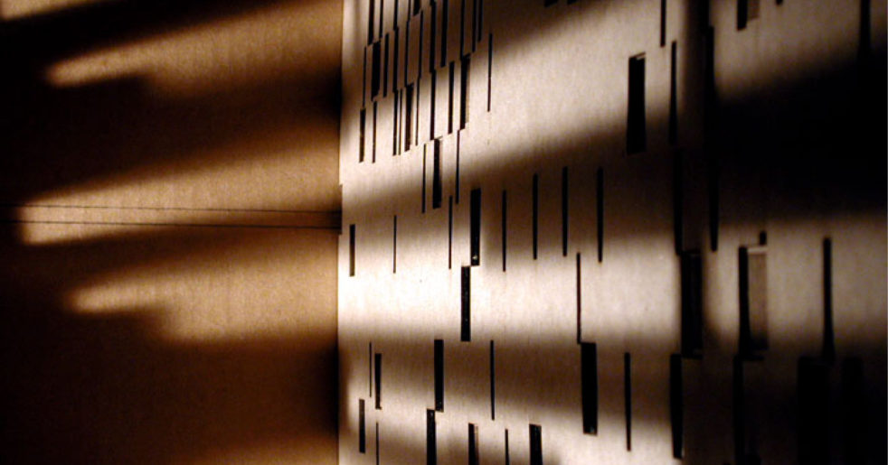 Photo of light streaming through designed openings in a cardboard structure