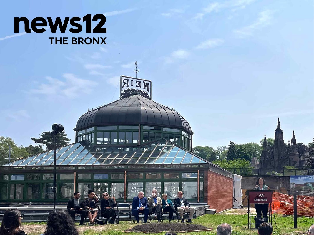 Photograph of seven officials sitting in front of historic Weir Greenhouse.