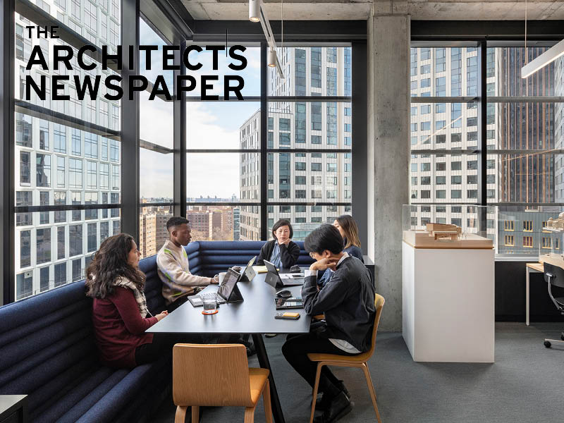 Photo of a four people sitting and working at a table surrounded by views of a city